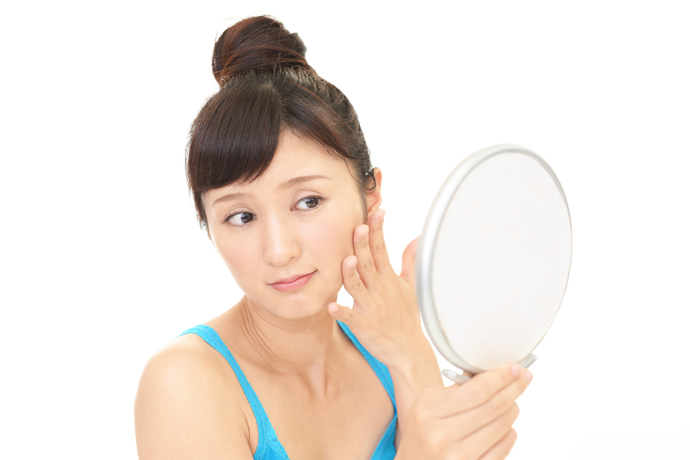 鏡で肌をチェックする女性